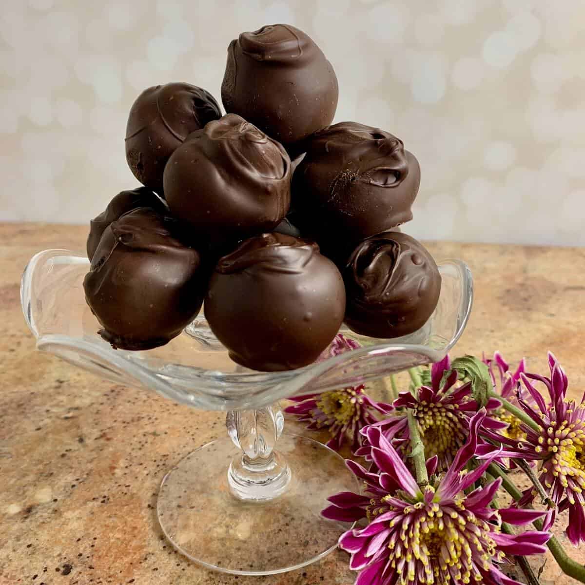 Truffle balls being rolled in a dish of cocoa powder.